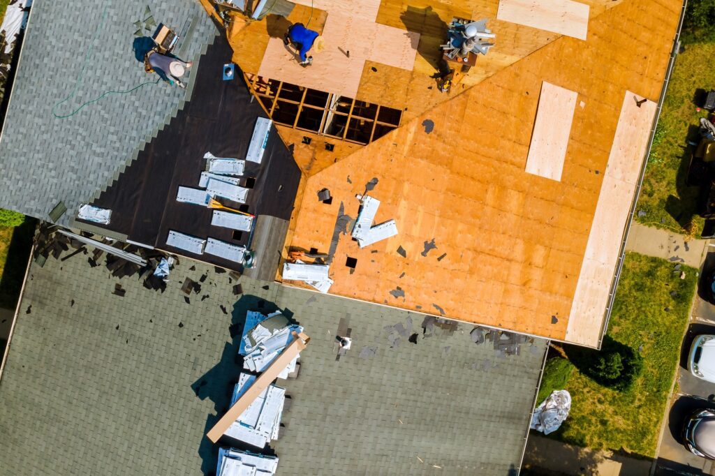A worker replace shingles on the roof of a home repairing the roof of home