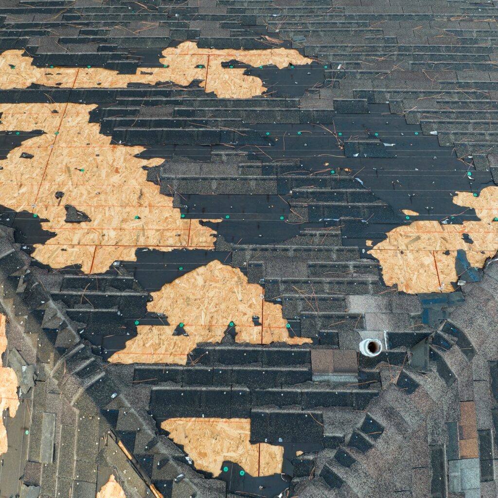 Ruined rooftop in need of repair. Wind damaged house roof with missing asphalt shingles in Ashburn, VA